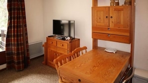 A small room with a wooden desk, a television, a cabinet, and a plaid curtain. - 10m from ski slopes, 1st floor, balcony, ski locker, 20m², Les Orres (Les Orres)