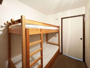 A bunk bed in a room with a door and a carpeted floor.