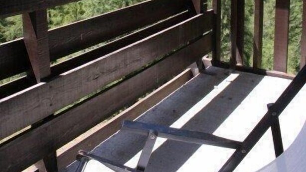 Une terrasse en bois avec un banc donnant sur un paysage montagneux.
