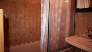 Une salle de bain avec une baignoire, un lavabo et un rideau de douche.