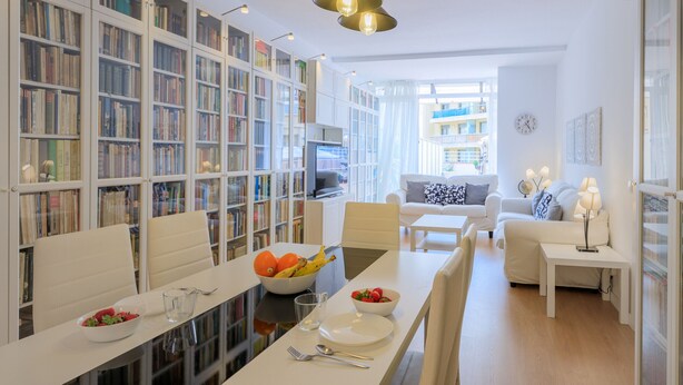 A modern living room with a dining area, white furniture, and bookshelves filled with books. - Apartment with private terrace, 3 bedrooms, Eixample (Barcelona)