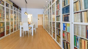 A library with white bookshelves, a table with chairs, and a hanging light fixture. - Apartment with private terrace, 3 bedrooms, Eixample (Barcelona)