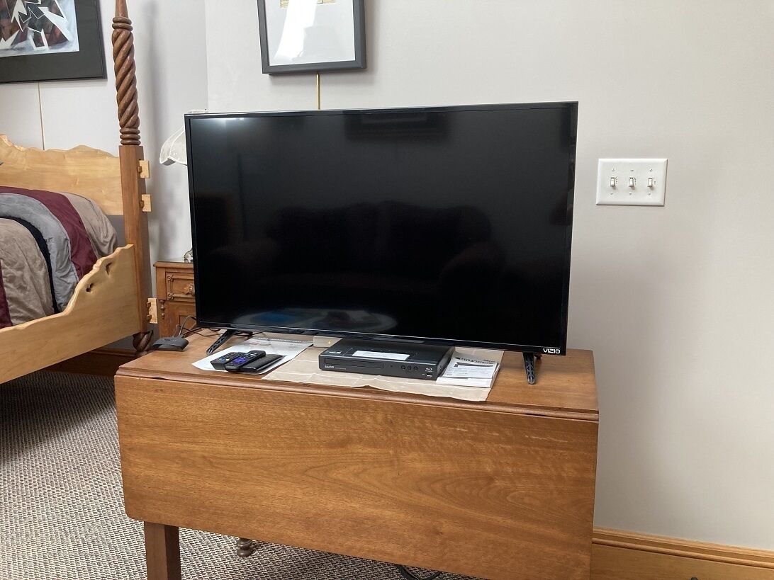 Un meuble en bois pour la télévision, sur lequel est posé un téléviseur à écran plat, un lecteur DVD et une télécommande.