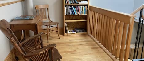 A cozy reading nook with a wooden rocking chair, a small table, and a bookshelf filled with books.