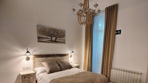 Una camera da letto con un letto, lampade sui comodini, un lampadario, un tavolo e una sedia.