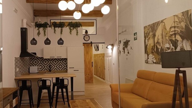 Una cucina moderna con zona pranzo, pavimento in legno e illuminazione a sospensione.