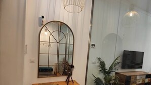 Un soggiorno moderno con un grande specchio, una consolle in legno e una bicicletta d'epoca.