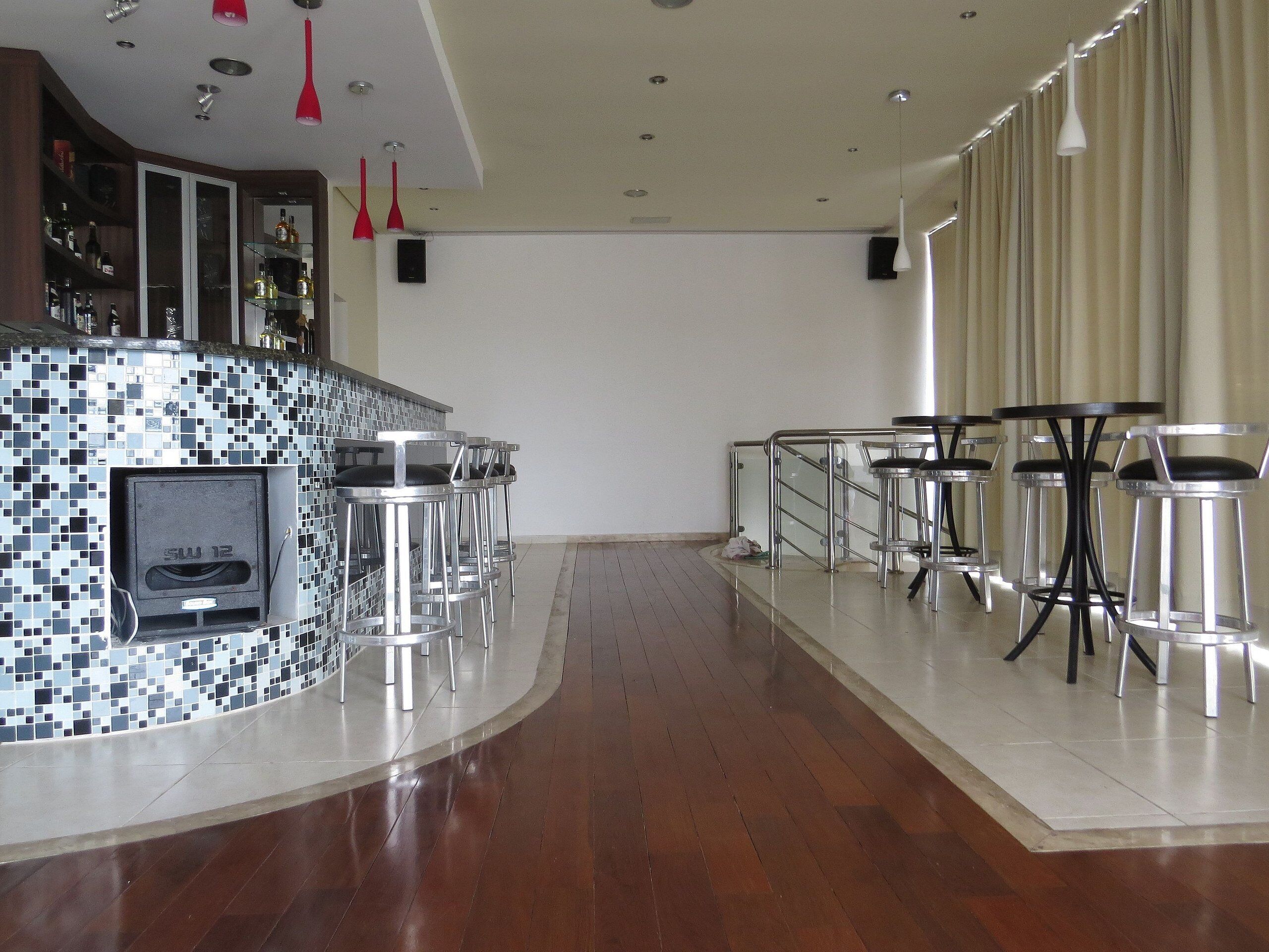 Un espace bar moderne avec un comptoir orné de mosaïques, des tabourets de bar en acier inoxydable et un barbecue intégré.