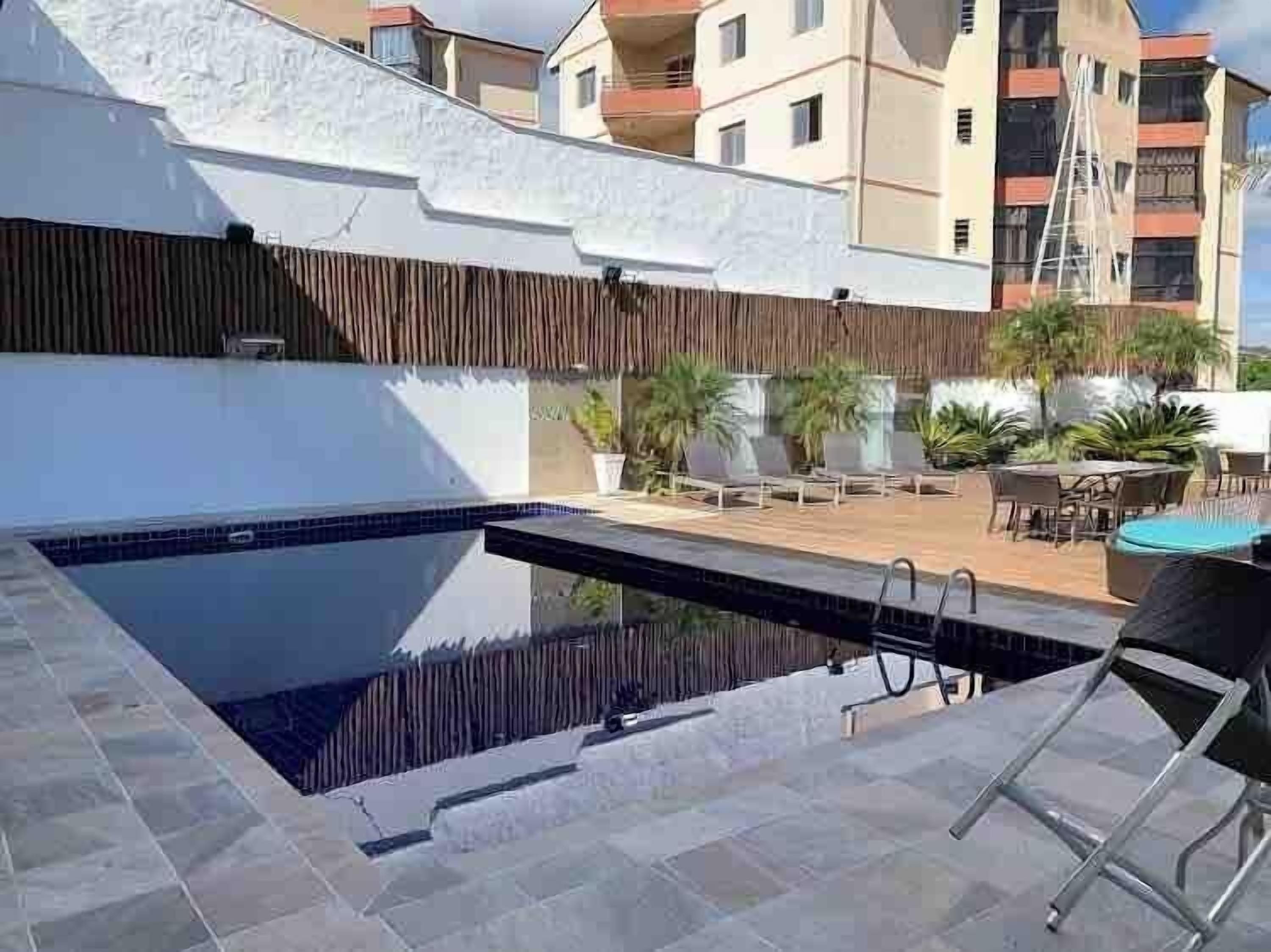 A rooftop pool area with a clear view of the surrounding buildings and a wooden fence.