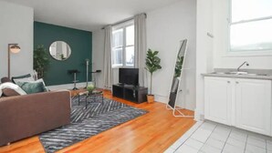 A modern living room with a sofa, a coffee table, a TV, and a large window.