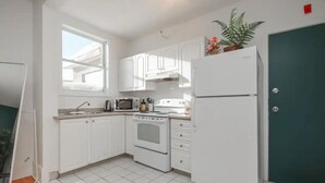 A compact kitchen with white cabinets, a microwave, an oven, and a refrigerator.