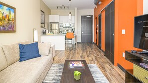 A modern living room with a sofa, coffee table, and a painting on the wall. - Revisn Executive Downtown Raleigh Apartment (Raleigh)