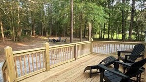 Een houten terras met een balustrade, omgeven door bomen.
