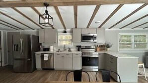 Een moderne keuken met roestvrijstalen apparatuur, houten balken en een groot eiland.