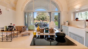 A modern kitchen with a large island, a view of the outdoors, and various kitchen appliances.