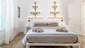 A bedroom with a bed, two bedside tables, a wall-mounted light fixture, and a door. - Villa in Carovigno with 3 bedrooms sleeps 6 (Carovigno)