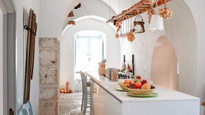 A kitchen with a central island, archways, hanging lights, and a view into another room.