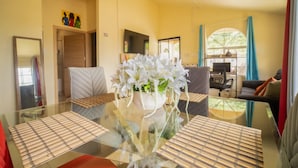 A modern living room with a glass coffee table, white floral centerpiece, and a sofa. - Casia Villa (Montego Bay)