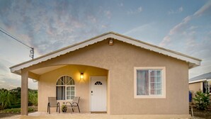 A single-story house with a covered porch, a door, and a window. - Casia Villa (Montego Bay)