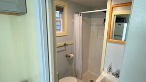 Ein Badezimmer mit Toilette, Dusche, Waschbecken und einem Fenster.