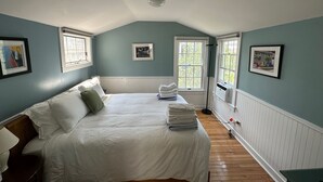 Ein Schlafzimmer mit einem großen Bett, zwei Fenstern und einer Heizung.