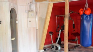 Un gimnasio pequeño con una bicicleta estática, una barra de dominadas y un saco de boxeo.