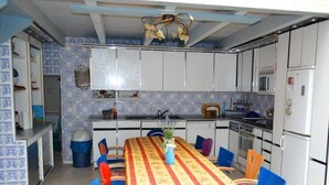 Una cocina compacta con armarios blancos, una isla central y una mesa de comedor con sillas.