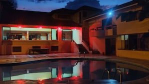 A modern house with a swimming pool, a covered patio, and a staircase leading to a second floor.