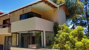 A two-story house with a balcony, a staircase, and a glass door leading to the entrance.