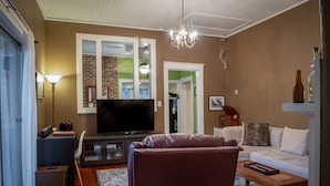 Ein Wohnzimmer mit Flachbildfernseher, Ledersessel, Sofa und Couchtisch aus Holz.