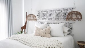 Een bed met een witte dekbedovertrek en een gebreide plaid.