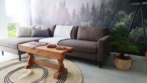 Een woonkamer met een bank, een houten salontafel en een grote plant.
