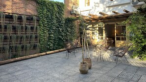 Un patio con paredes de ladrillo, una pérgola y mobiliario exterior.