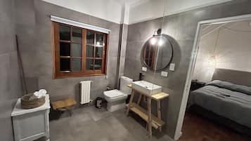 Un bany petit i funcional amb vàter, rentapel i finestra.