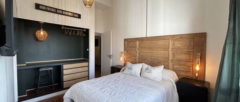 A bedroom with a large bed, a wooden headboard, a wardrobe, and a hanging light fixture.