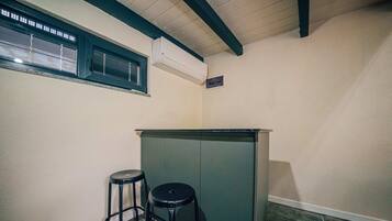 A small, enclosed space with a kitchenette area, including a countertop and two stools.