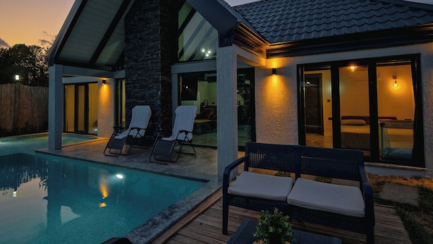 Une maison moderne dotée d’une piscine, d’un espace salon extérieur et d’un patio.