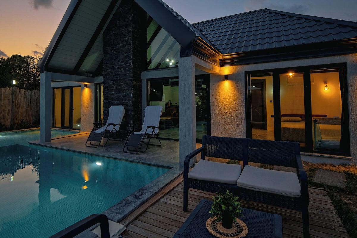 Een modern huis met een zwembad, buitenmeubilair en een terras.