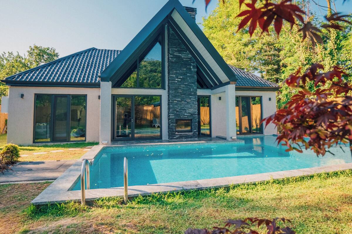 Een modern huis met zwembad, grote ramen en een stenen gevel.