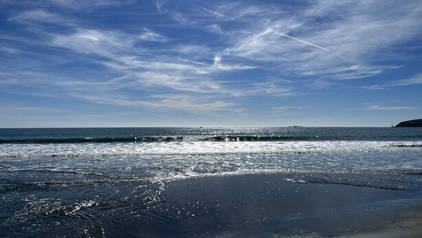 A beach with a clear sky and sunlight reflecting off the water.