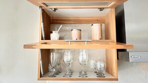 A kitchen with a wooden shelf unit containing kitchenware and wine glasses. - Studio in Bariloche for two people (San Carlos de Bariloche)