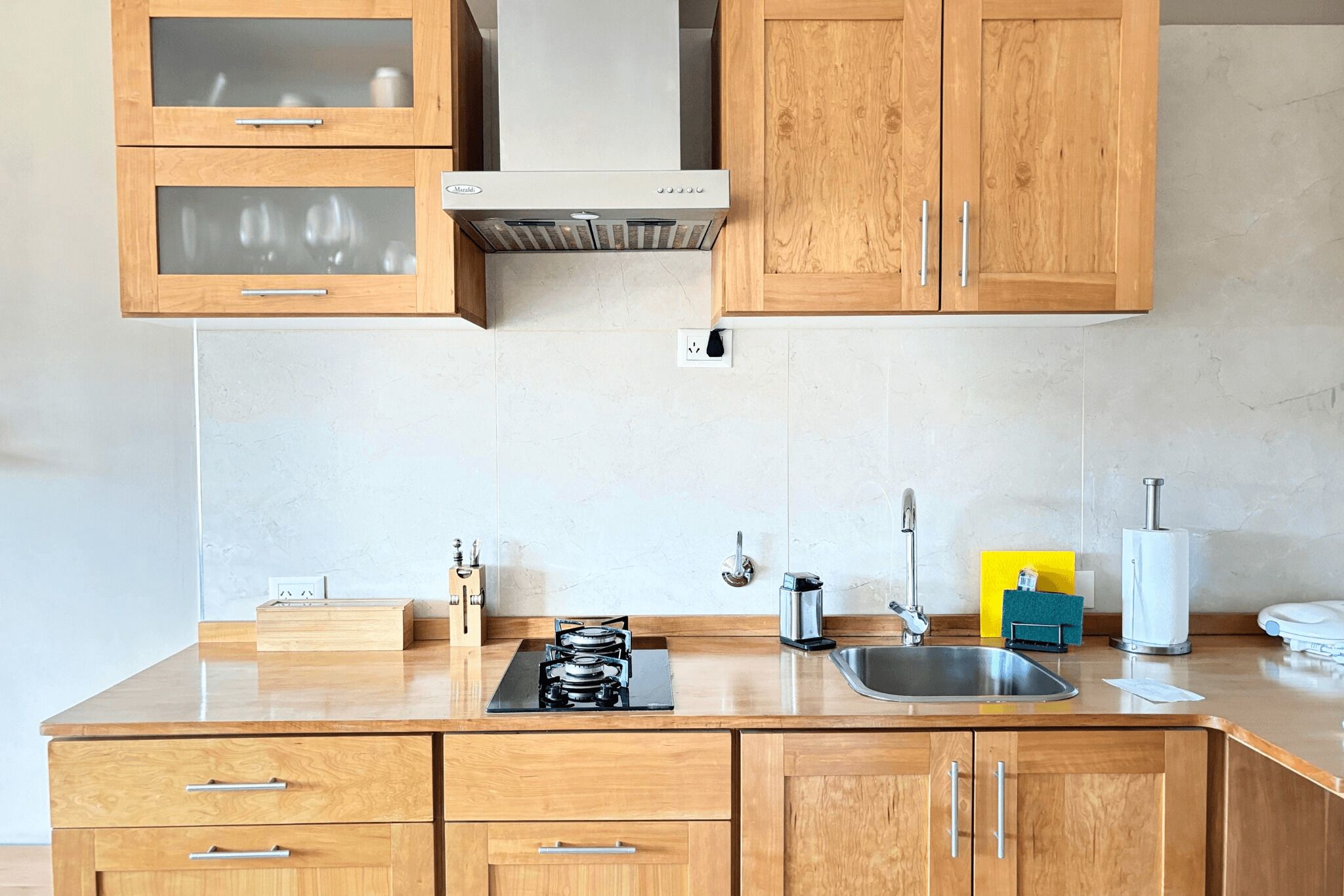 A modern kitchen with wooden cabinets, a stainless steel sink, and a built-in range hood.