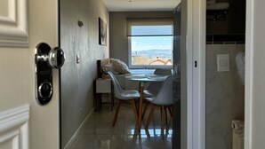 A modern hotel room with a dining area, a large window with a view of the mountains, and a bathroom with a towel rack. - Studio in Bariloche for two people (San Carlos de Bariloche)