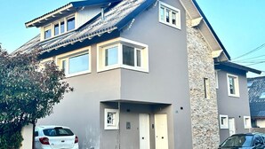 A two-story building with a grey facade, a stone accent wall, and a sloped roof. - Studio in Bariloche for two people (San Carlos de Bariloche)