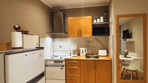A compact kitchen with a refrigerator, stove, microwave, and wooden cabinets. - Studio in Bariloche for two people (San Carlos de Bariloche)