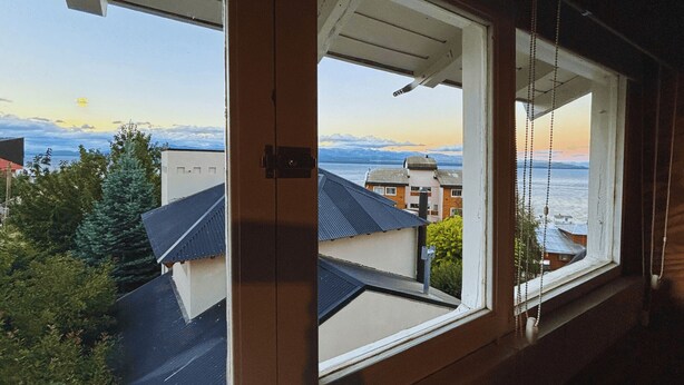 Vista desde una ventana que da a una zona residencial con casas y una masa de agua.