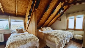 Un dormitorio con dos camas, vigas de madera, una ventana y un radiador.