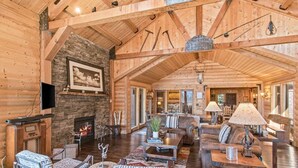 A spacious log cabin interior with a fireplace, leather furniture, and a stone accent wall. - Amazing Lakefront Getaway-sleeps 18 guests, w/private dock, gameroom, spa & more (Hayden)