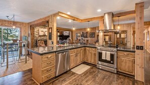 A spacious kitchen with wooden cabinetry, stainless steel appliances, and a large island. - Amazing Lakefront Getaway-sleeps 18 guests, w/private dock, gameroom, spa & more (Hayden)