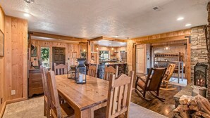 A rustic wooden interior with a dining area, kitchen, and fireplace. - Amazing Lakefront Getaway-sleeps 18 guests, w/private dock, gameroom, spa & more (Hayden)